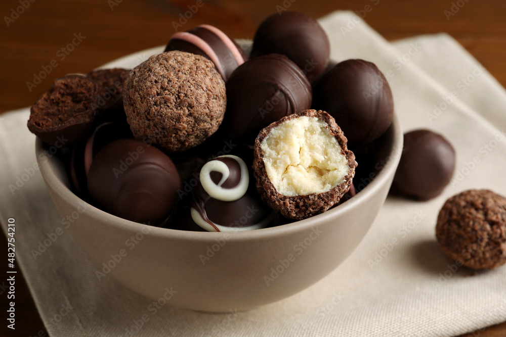 Bowl with many different delicious chocolate truffles on wooden table Bowl with many different delicious chocolate truffles on wooden table
