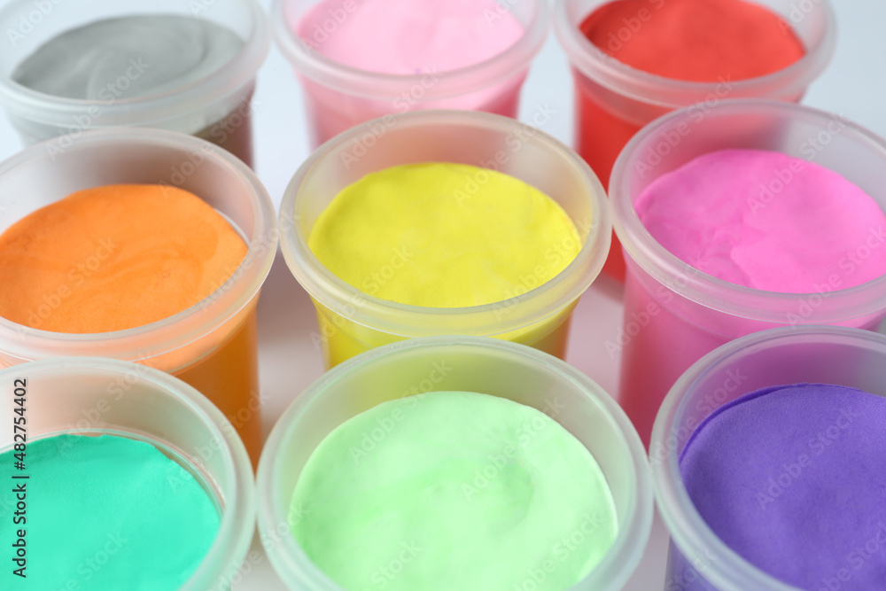 Plastic containers with colorful play dough on white background, closeup Plastic containers with colorful play dough on white background, closeup