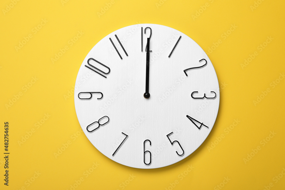 Modern clock on yellow background, top view Modern clock on yellow background, top view