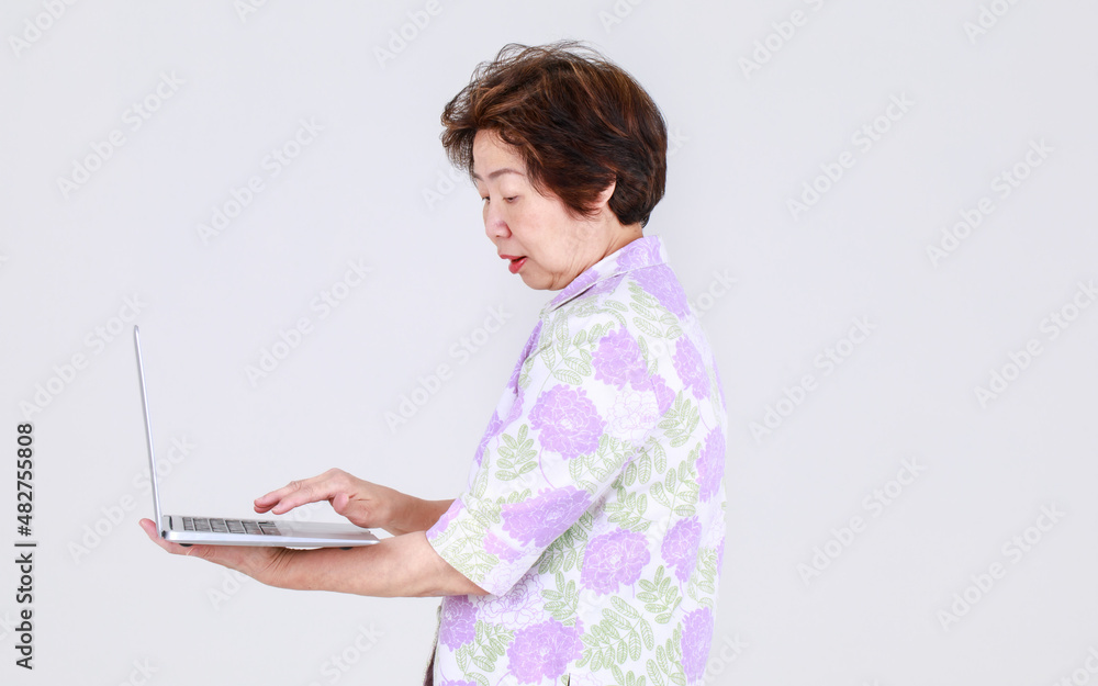 Senior Asian aunt as elderly teacher playing business laptop to explain sale promotion and public advertising message of electronic device Senior Asian aunt as elderly teacher playing business laptop to explain sale promotion and public advertising message of electronic device