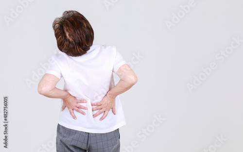 Elderly aunt stand tilt and twist with hands on waist as disappointed on body disease and tired of back pain
