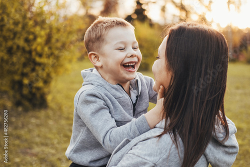 Portrait of a boy happily spending time with his mother in the park. Modern lifestyle. Family care. Smiling happy child.