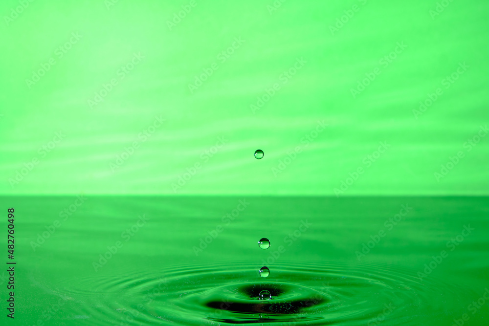 Splash water after drop falls.Green abstract background with drop in water. Splash water after drop falls.Green abstract background with drop in water.