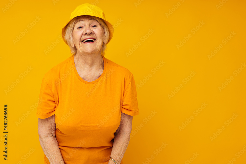 Portrait of an old friendly woman in casual t-shirt yellow panama cropped view