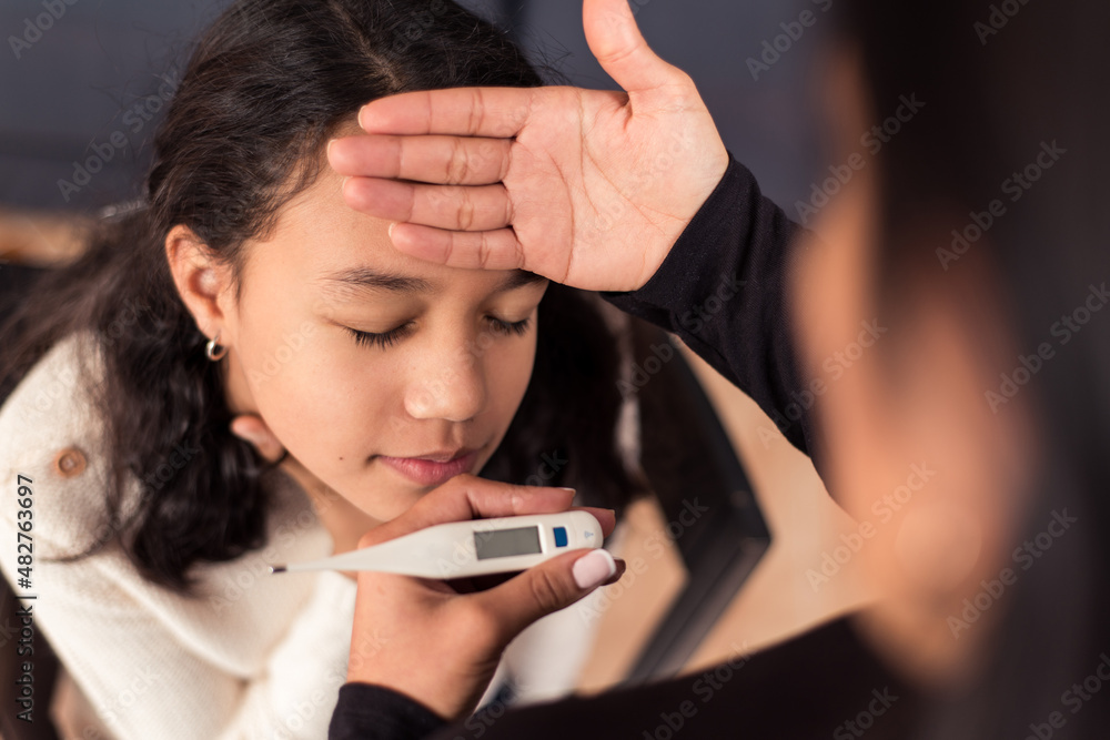 Little girl with symptoms of coronavirus has a sore throat. Mother checks her temperature to keep her at home. Little girl with symptoms of coronavirus has a sore throat. Mother checks her temperature to keep her at home.