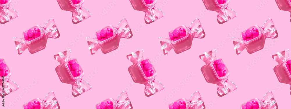 Transparent candy shaped box with sweet heart lollipops with hard shadow on pink background  copy space. The concept of Valentines day, mothers day. Banner. pattern