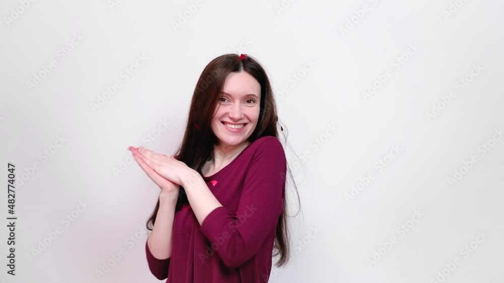 Happy woman in red dress under falling red heart-shaped confetti looks at camera. Valentine's Day concept. Happy woman in red dress under falling red heart-shaped confetti looks at camera. Valentine's Day concept.