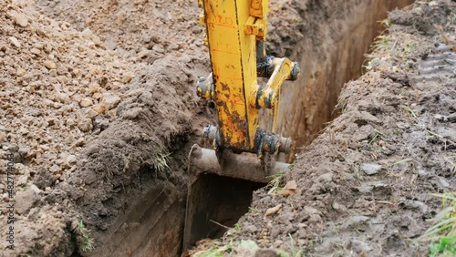 Mini excavator digs a trench to lay pipes. excavator bucket close up.