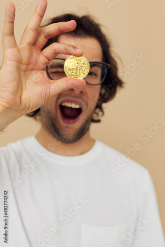 handsome man in a white T-shirt with Bitcoin cryptocurrency beige background