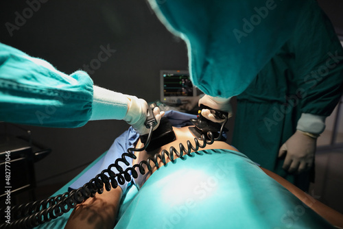 Foto Closeup image of professional concentrated surgical team performing CPR with defibrillator on patient in hospital operating room or emergency room