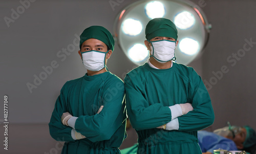 Professional surgical team arms crossed with patient blurred background on hospital bed in hospital operating room. Medical technology, treatment, healthcare, surgery and health insurance concept photo