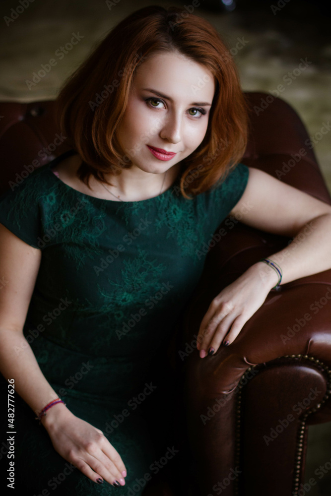 Naklejka premium red-haired woman in green dress posing
