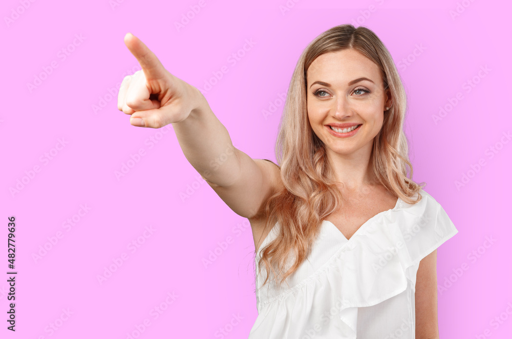 Young smiling woman pointing to copy space isolated on color background Young smiling woman pointing to copy space isolated on color background