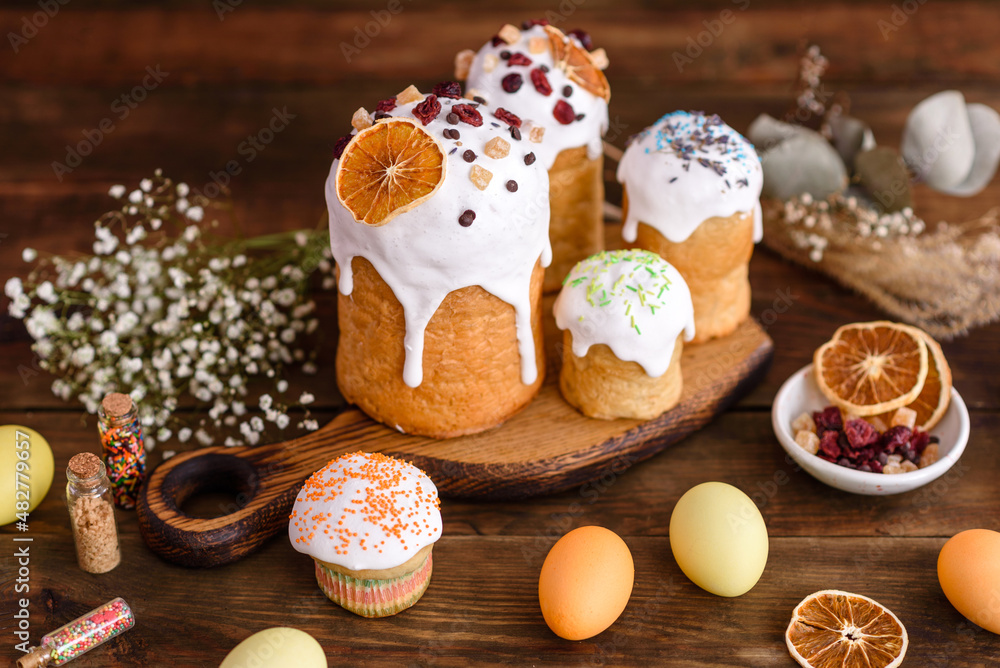 Easter holiday concept. Easter cakes (orthodox kulich), willow, painted eggs and candle on rustic wooden table