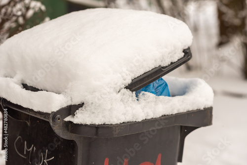 Winter garbage bin covered by snow. Environmental object.