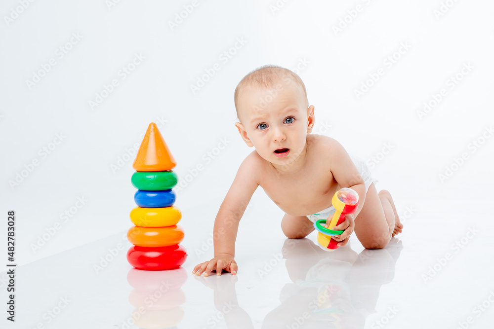 a little baby boy in a diaper crawls on a white background playing a multi-colored pyramid , studio shooting a little baby boy in a diaper crawls on a white background playing a multi-colored pyramid , studio shooting