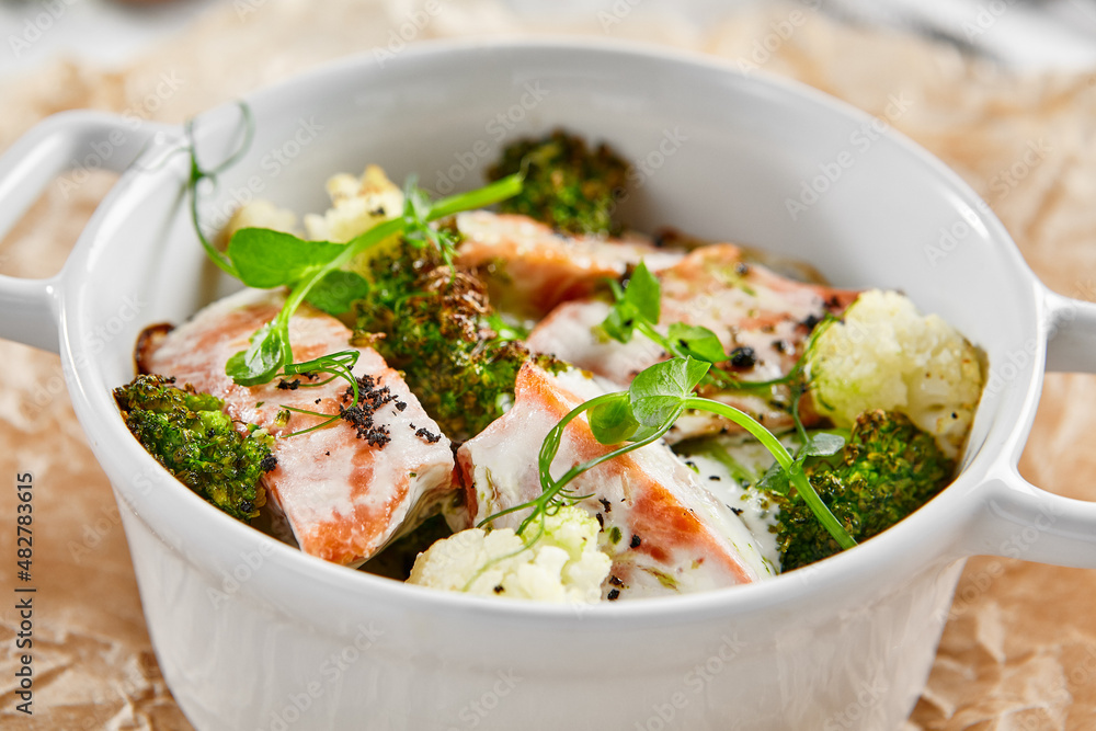 Healthy eating: steamed vegetables with salmon. Healthy salmon meal with broccoli and cauliflower. Casserole with fish and broccoli for lunch. Broccoli dish in diet menu. Cooked fish and veggies.