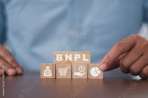 Businessman pressing his finger on the wooden cubes with BNPL with online shopping icons. BNPL Buy now pay later online shopping concept.