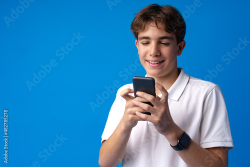Teenager using a phone isolated on blue background