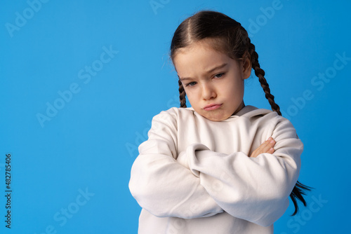 Portrait of upset little girl on blue background