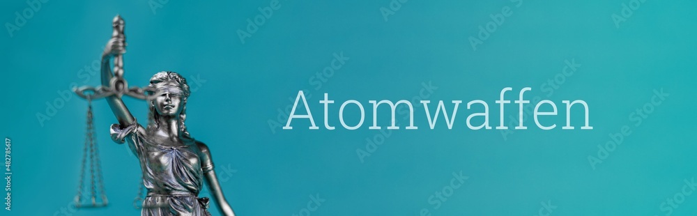 Atomwaffen (Kernwaffen). Nahaufnahme einer Justitia Statue. Wort auf blauem Untergrund. Panorama Atomwaffen (Kernwaffen). Nahaufnahme einer Justitia Statue. Wort auf blauem Untergrund. Panorama