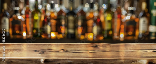 Fotografiet Wooden board and beautiful bokeh shelves with alcohol bottles at the background