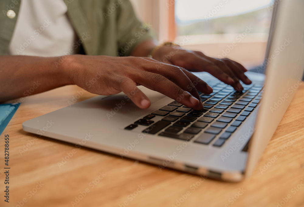 Young adult black male typing on laptop. Close up of hands, working from home, sitting at modern styled kitchen counter. Young adult black male typing on laptop. Close up of hands, working from home, sitting at modern styled kitchen counter.