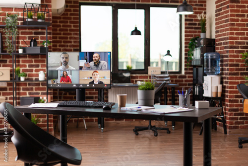 Video call communication with colleagues on computer in empty business office. Monitor with online video teleconference used for remote meeting with team of businesspeople at work.