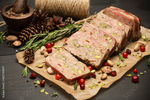 Sliced Traditional French terrine covered with bacon on dark wooden background