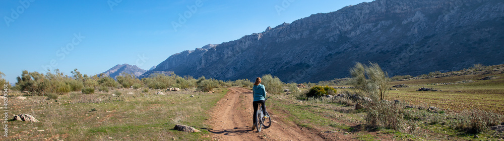 panorama view of woman on mountain bike in countryside