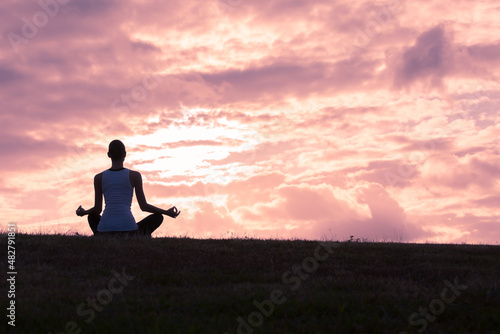 Woman doing meditating at sunset