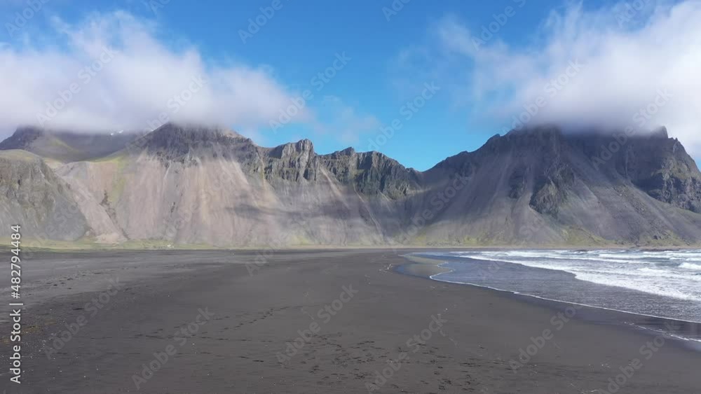 Flying over a sandy beach on the Atlantic ocean coast. Waves washing the shore. Stokknes peninsula, Vestrahorn mountains, Hofn, Iceland. Aerial drone view Flying over a sandy beach on the Atlantic ocean coast. Waves washing the shore. Stokknes peninsula, Vestrahorn mountains, Hofn, Iceland. Aerial drone view