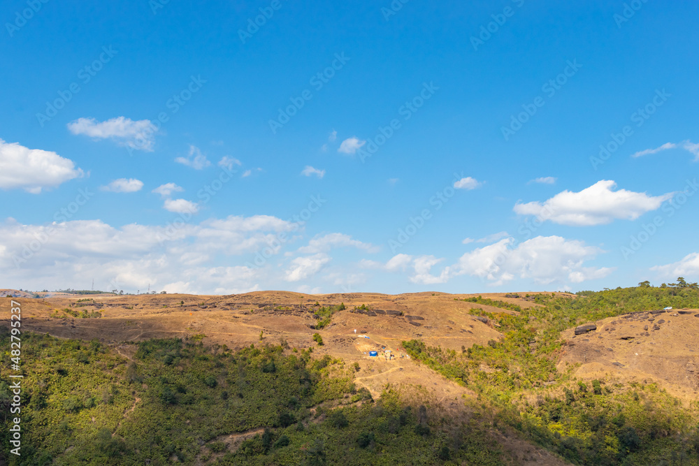 yellow grass mountain range with bright blue sky at morning from flat angle