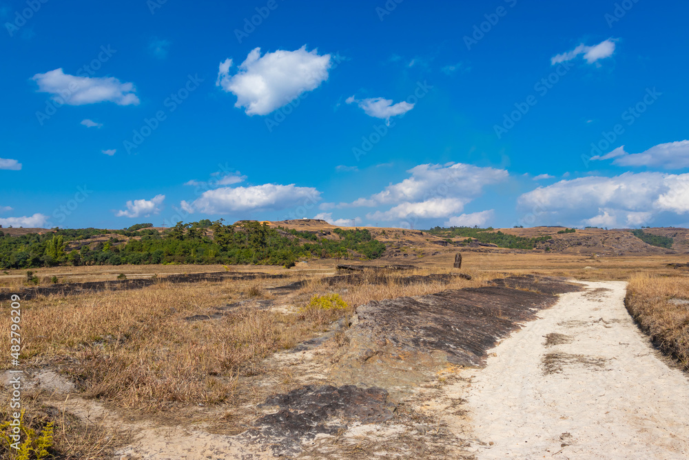 countryside fields with leading line of white sand bright and blue sky at morning from flat angle