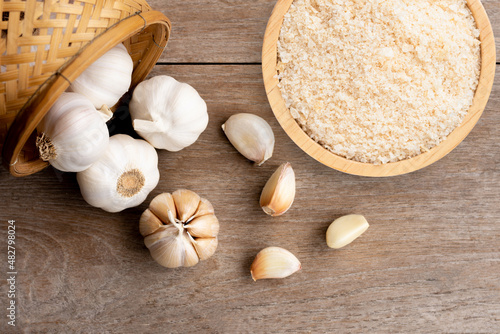 Obraz na płótnie Garlic powder in wooden bowl and bulb of garlic isolated on wooden table background