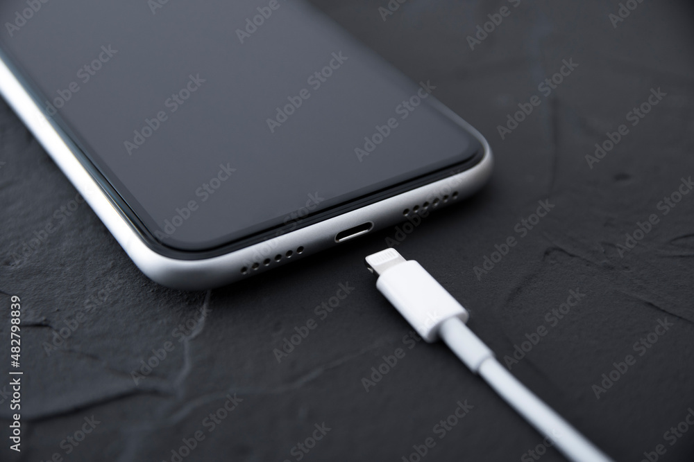 Mobile smart phone on wireless charging device on white background. Icon battery and charging progress lighting on screen.smartphones connected to power source.low battery level problems.Plugged Phone Mobile smart phone on wireless charging device on white background. Icon battery and charging progress lighting on screen.smartphones connected to power source.low battery level problems.Plugged Phone
