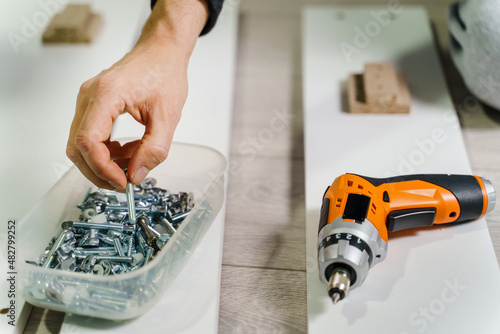 Fotografie Close up on midsection of unknown caucasian man holding electric screwdriver whi