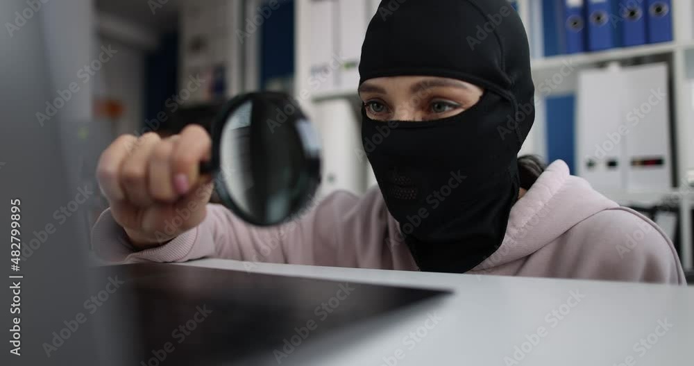 Man in balaclava looking at laptop screen with magnifying glass 4k movie Man in balaclava looking at laptop screen with magnifying glass 4k movie