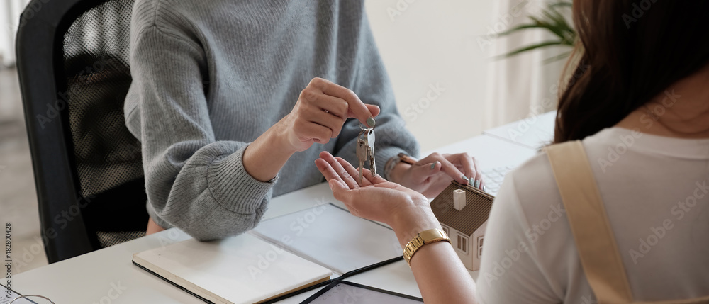 Fototapeta premium real estate agent holding house key to his client after signing contract agreement in office,concept for real estate, moving home or renting property