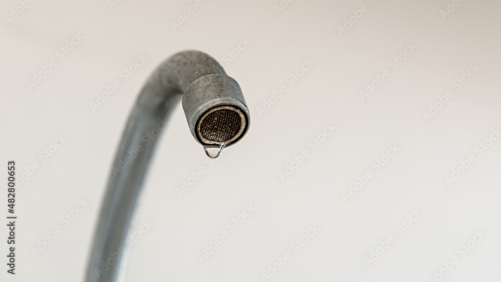 Water drop falling down from old rusty tap on blurred background of kitchen wall closeup Water drop falling down from old rusty tap on blurred background of kitchen wall closeup