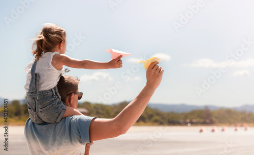 dad and daughter on his shoulders are going to launch paper airplanes into the sky