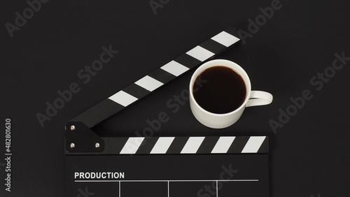 Black Clapper board and hot coffee white cup on black background.