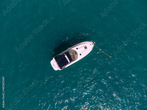 Small white boat with a blue roof siling across the sea, view from above. © Semachkovsky 