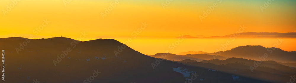 Obraz premium Beautiful landscape panorama in the Black Forest - View during the sunset in the mountains,hills, forest trees in the blackforest, with foggy fog and glowing sky.