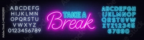 Take a Break neon quote on a brick wall.