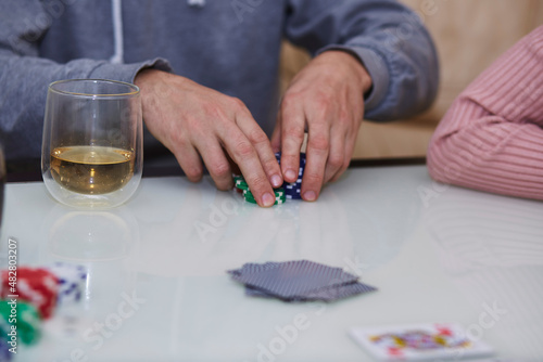 Man hands in a poker game. Chips, cards, glass of whiskey on the table with reflection. Lifestyle photography. Poker club