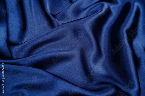The background is made of dark blue silk or satin, flowing with waves of fabric.