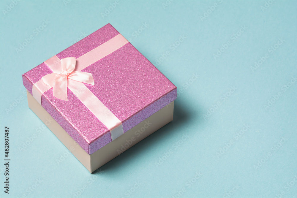 Violet gift box on a blue background. Birthday, mother's or valentine's day gift. Holiday and generosity concept Violet gift box on a blue background. Birthday, mother's or valentine's day gift. Holiday and generosity concept