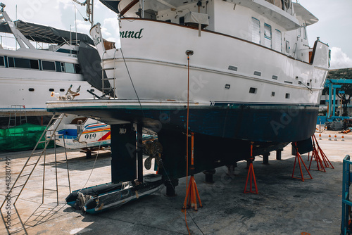 A huge white sailing yacht on the big black is standing on the repairing