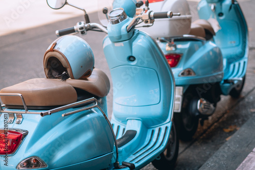 Small pretty blue motorbikes with helmets are parked near the roadway © Semachkovsky 